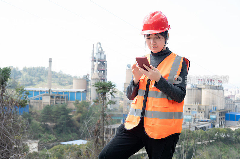 A female worker uses her mobile phone to communicate in a cement plant